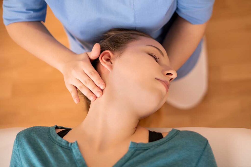 Clinician demonstrating a gentle spinal adjustment while a patient lies comfortably on an examination table.